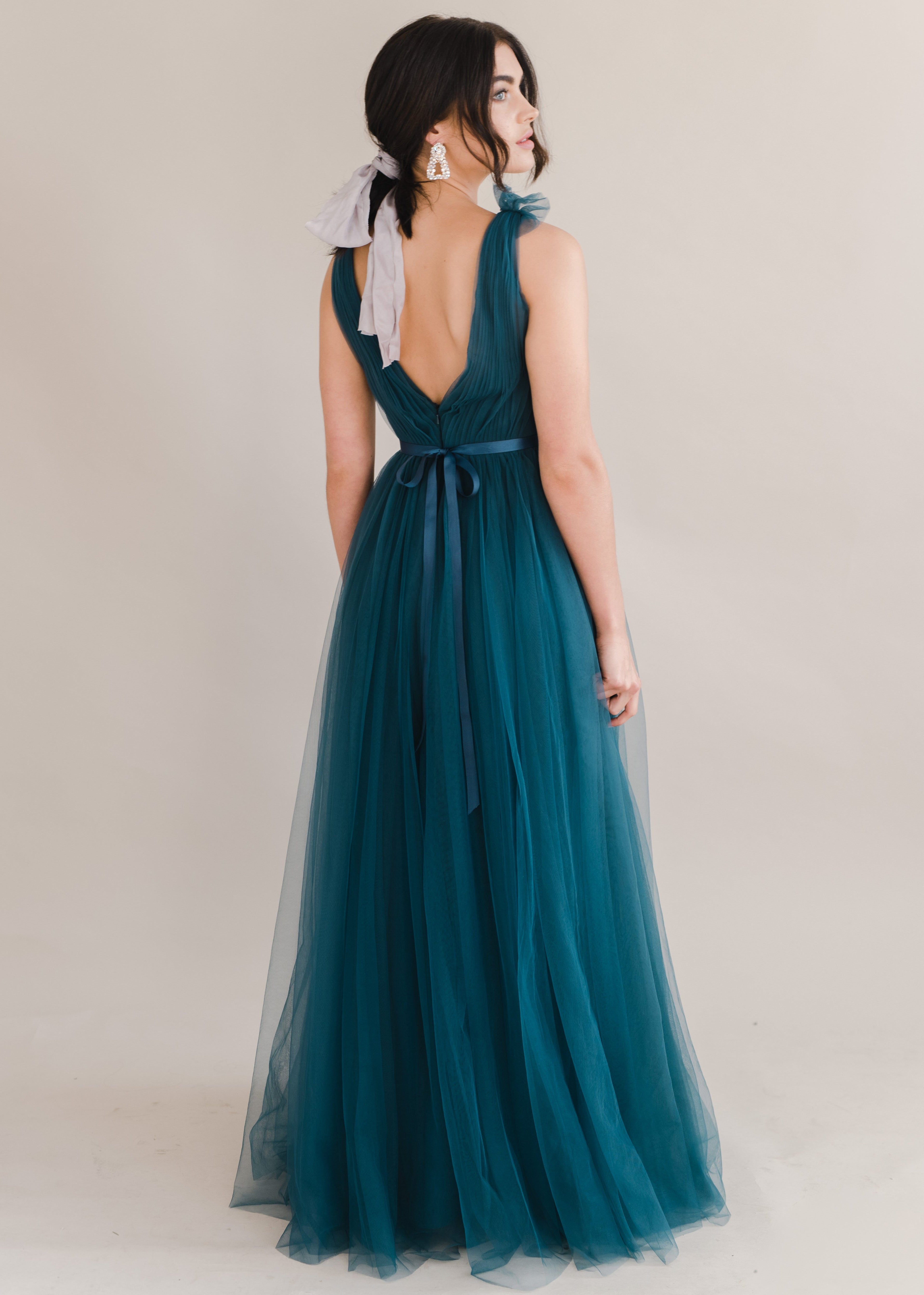 Woman wearing a long emerald dawn green bridesmaid dress with v neck and full skirt in tulle.