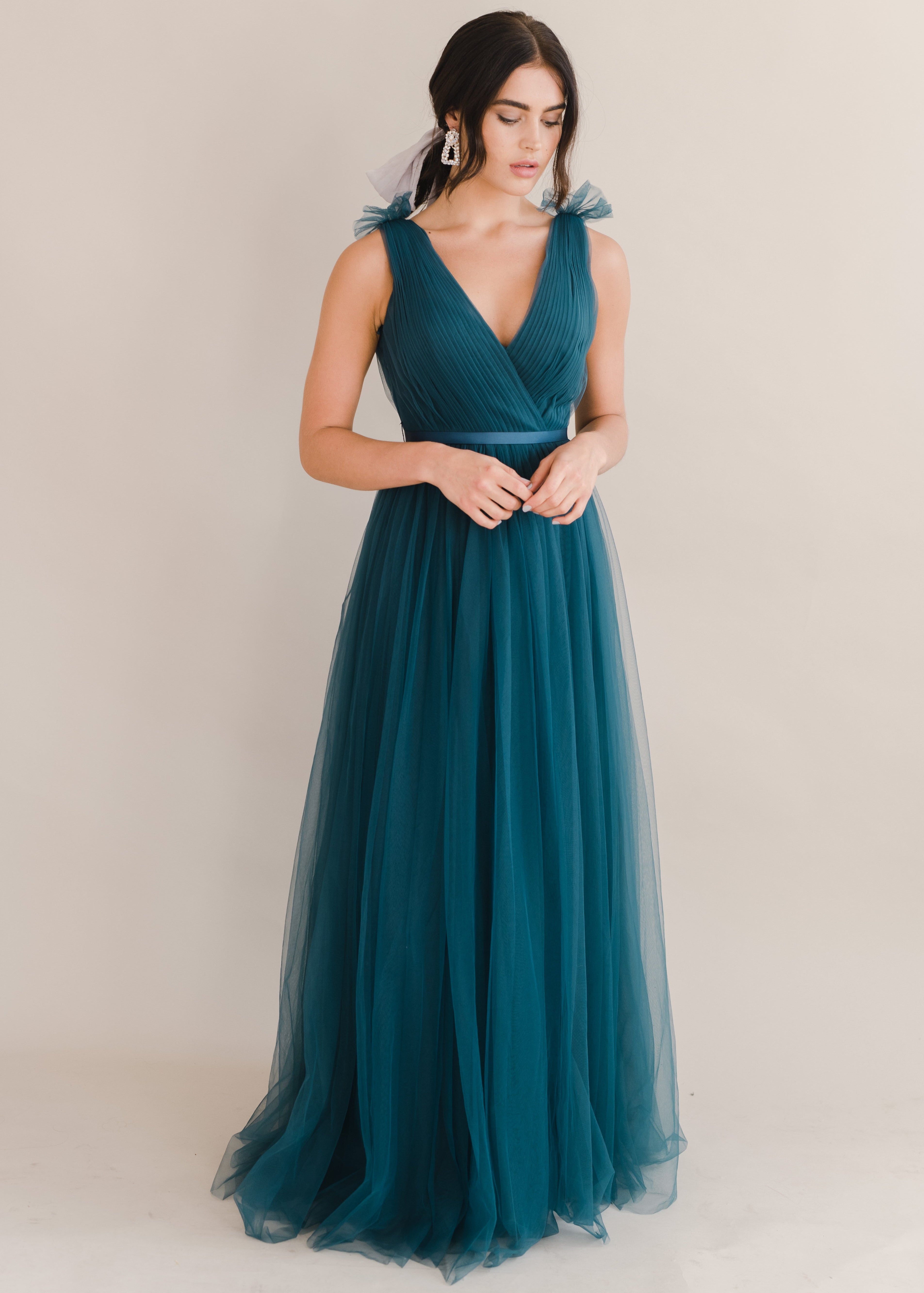Woman wearing a long emerald dawn green bridesmaid dress with v neck and full skirt in tulle.