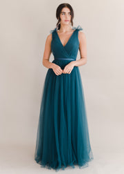 Woman wearing a long emerald dawn green bridesmaid dress with v neck and full skirt in tulle.