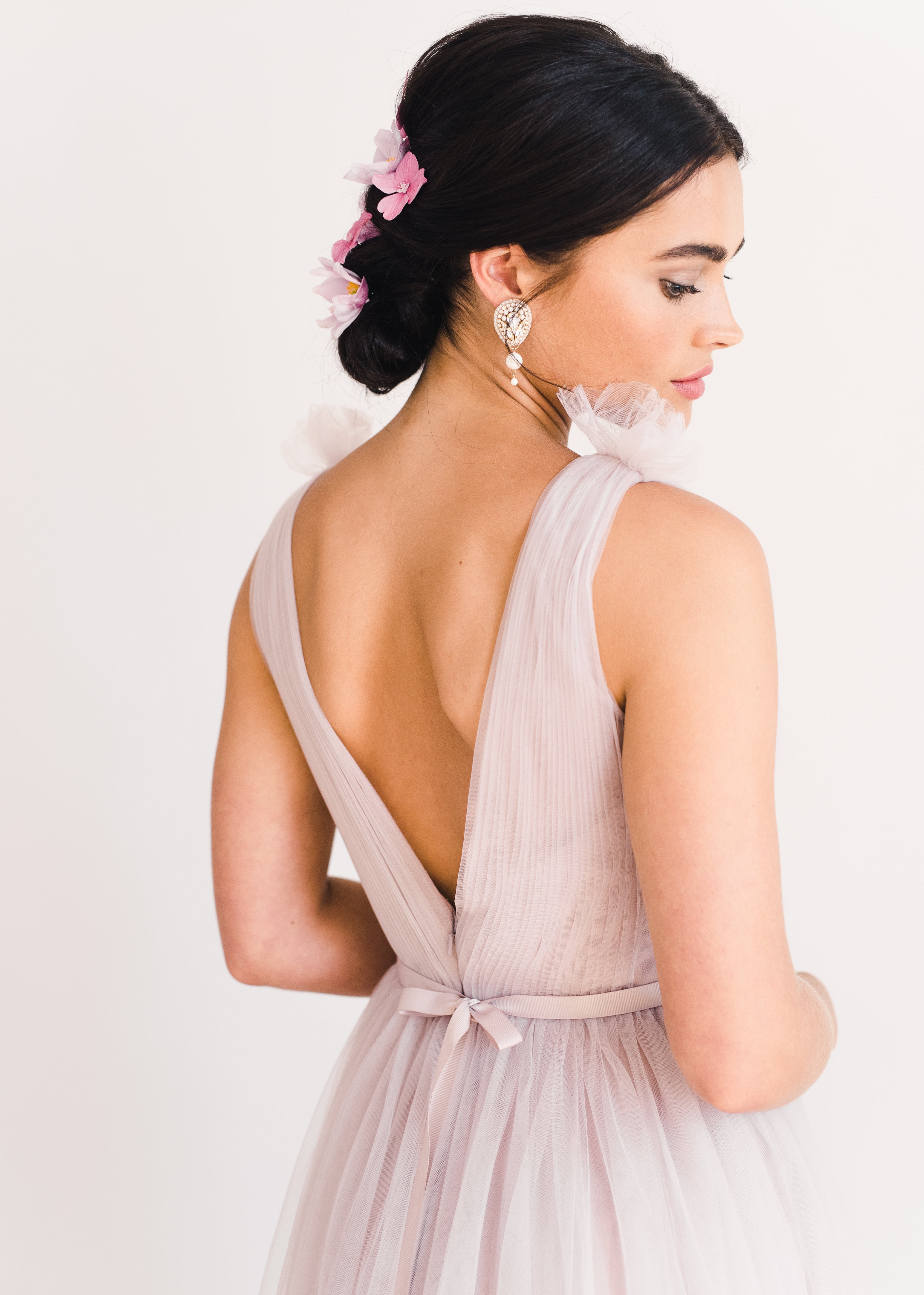 Woman wearing a long smoked blush pink bridesmaid dress with V neck and full skirt in tulle