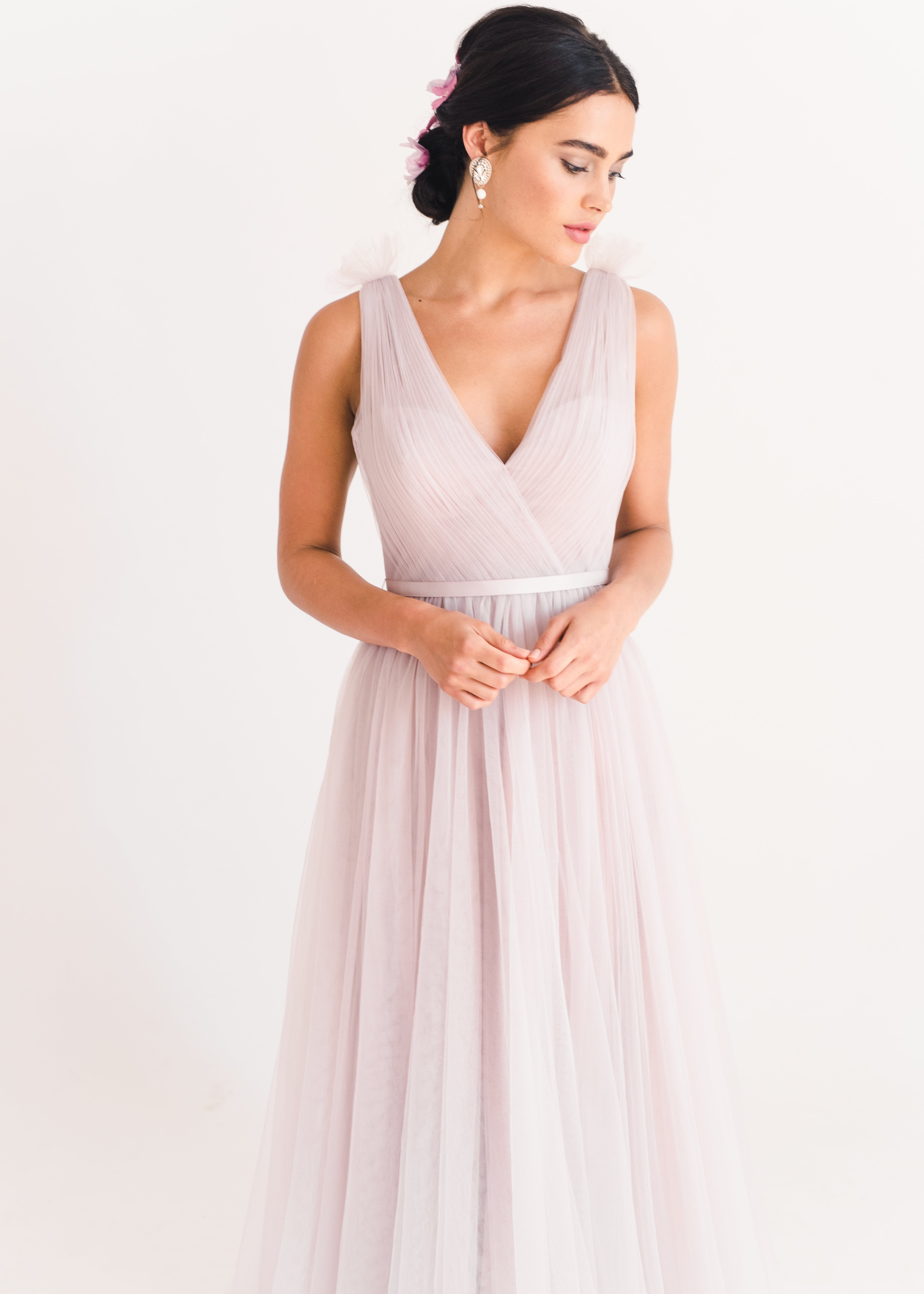 Woman wearing a long smoked blush pink bridesmaid dress with V neck and full skirt in tulle.