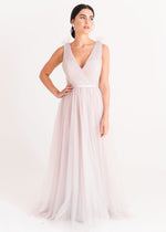 Woman wearing a long smoked blush pink bridesmaid dress with V neck and full skirt in tulle.