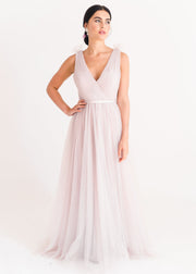 Woman wearing a long smoked blush pink bridesmaid dress with V neck and full skirt in tulle.