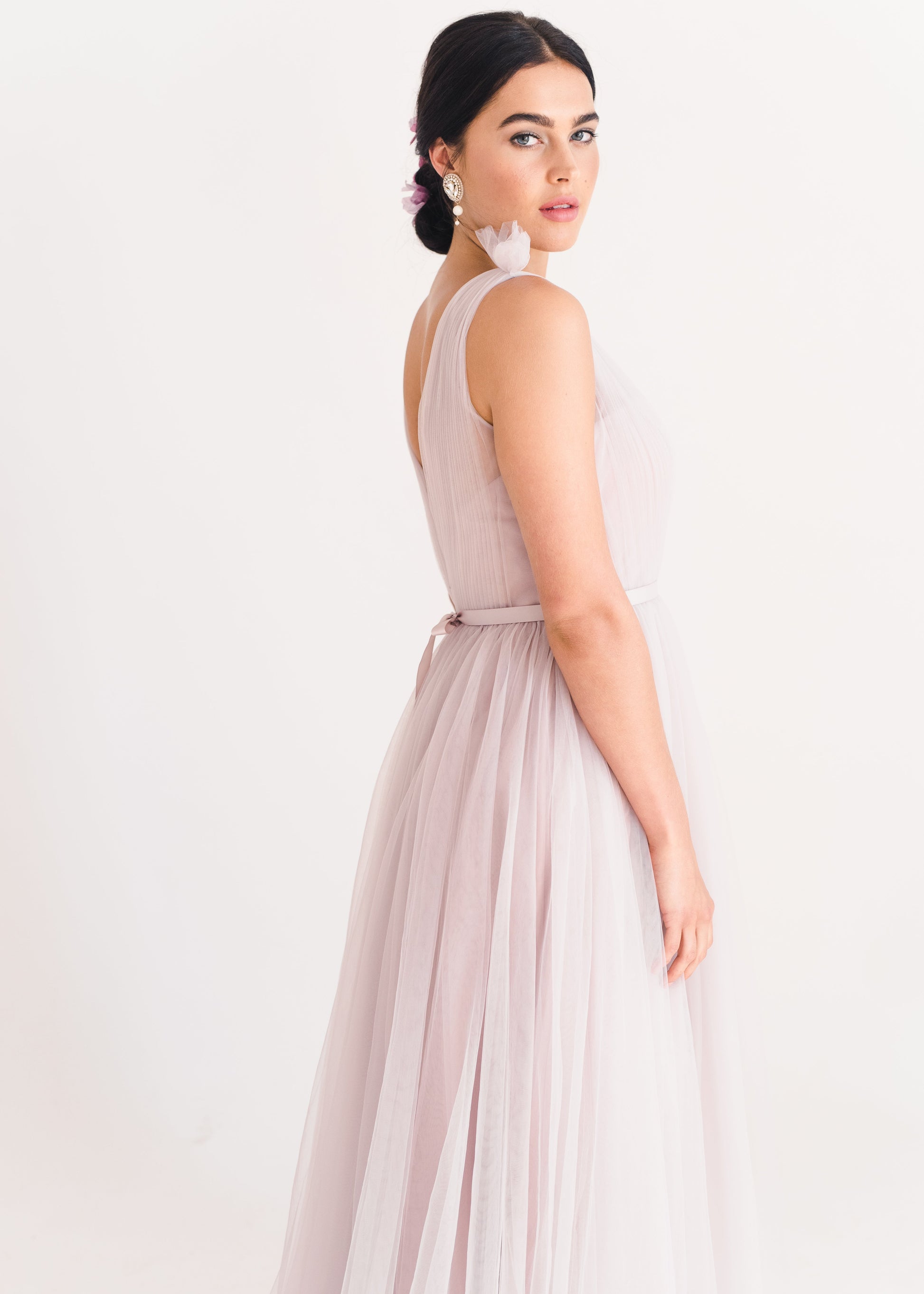 Woman wearing a long smoked blush pink bridesmaid dress with V neck and full skirt in tulle.