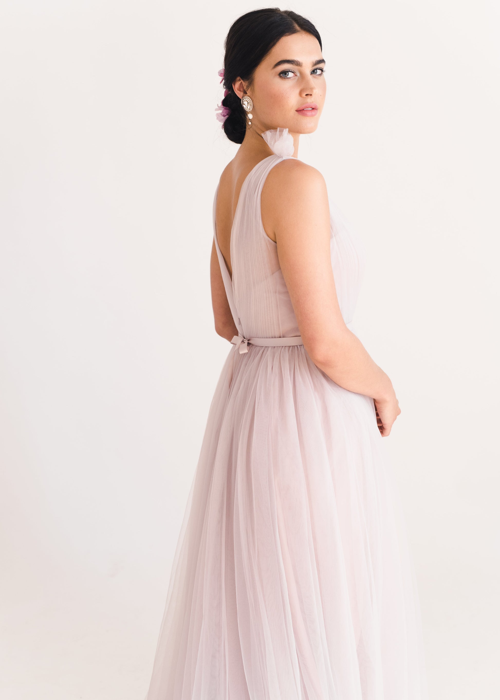 Woman wearing a long smoked blush pink bridesmaid dress with V neck and full skirt in tulle.