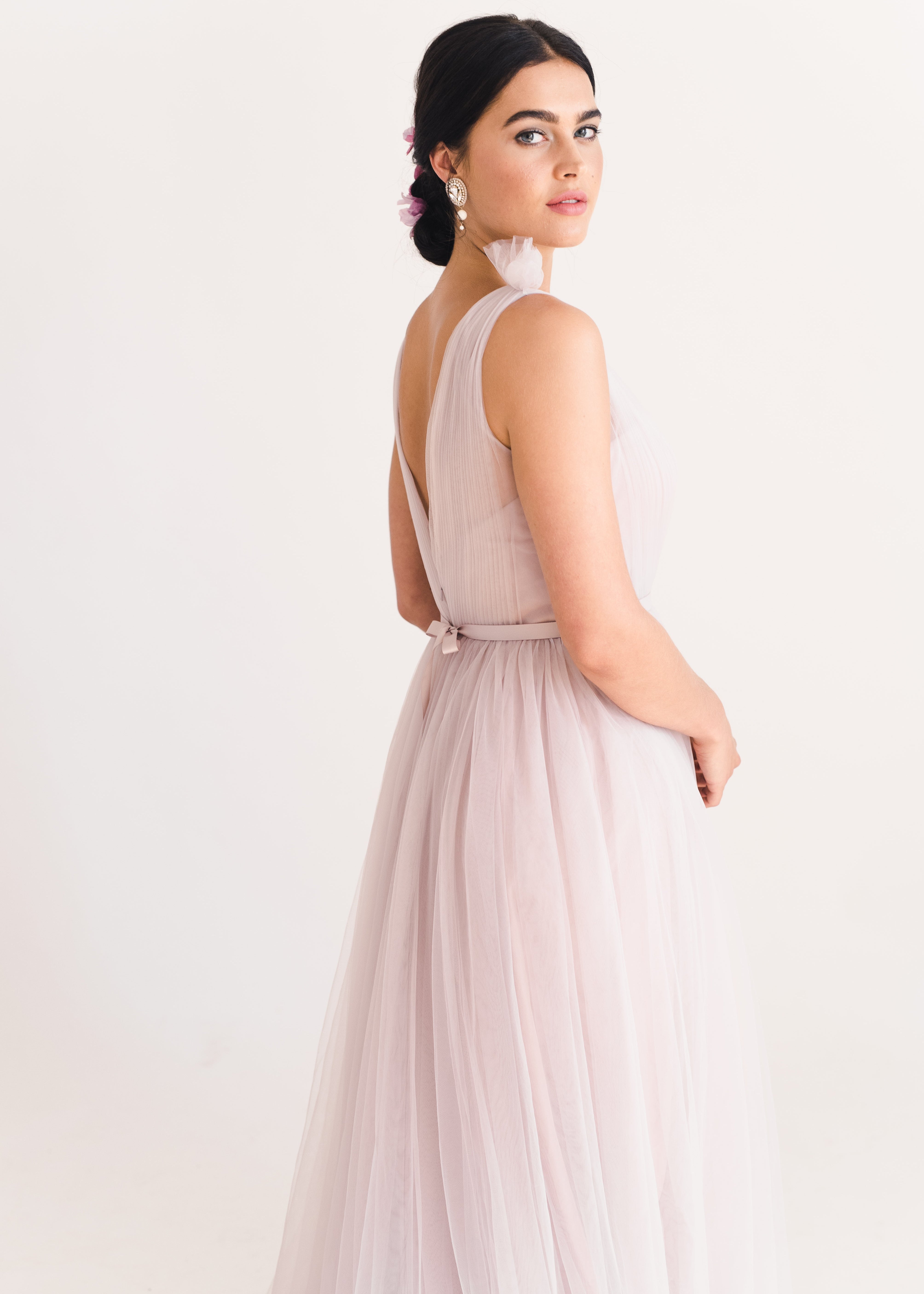 Woman wearing a long smoked blush pink bridesmaid dress with V neck and full skirt in tulle.