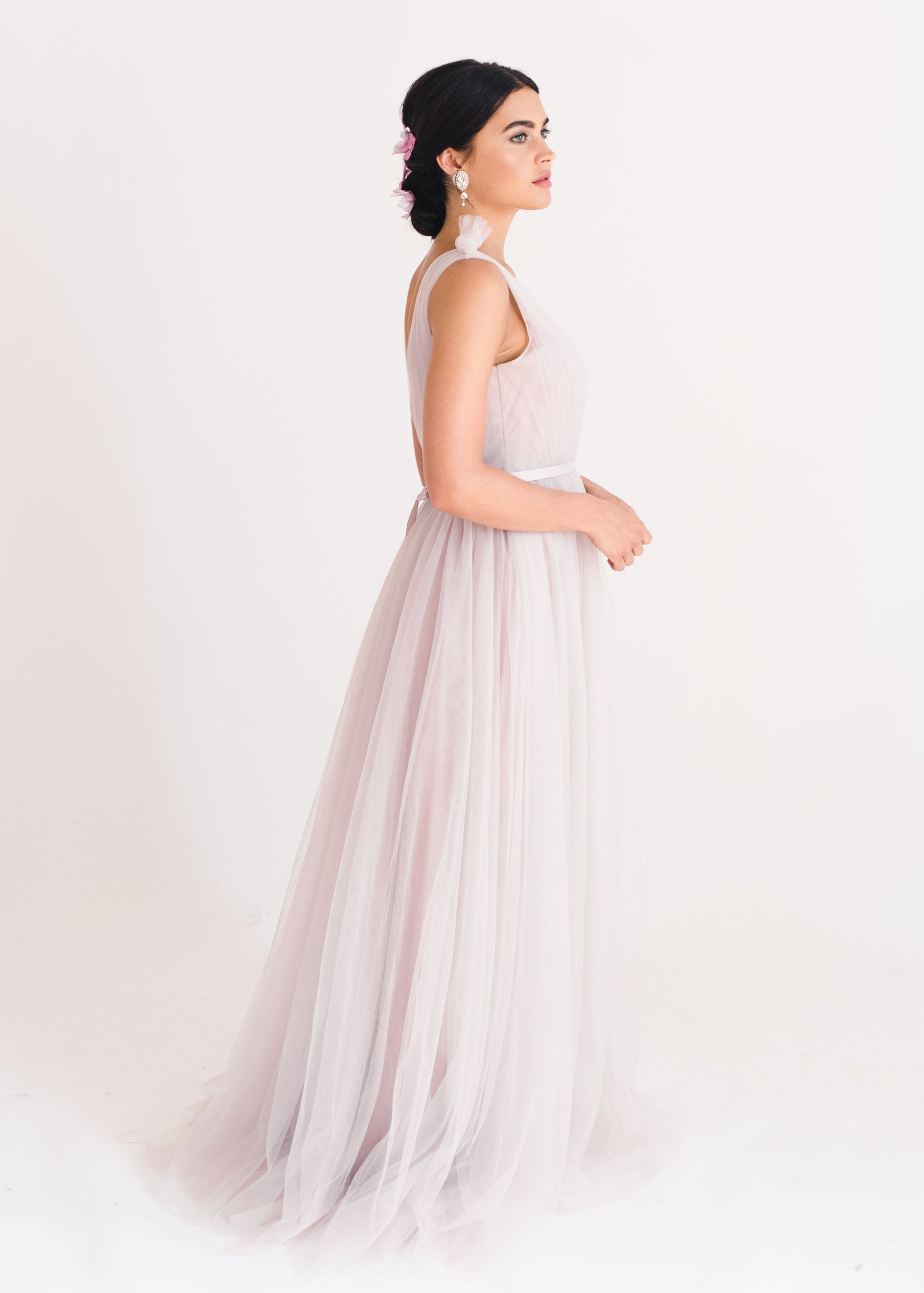 Woman wearing a long smoked blush pink bridesmaid dress with V neck and full skirt in tulle.