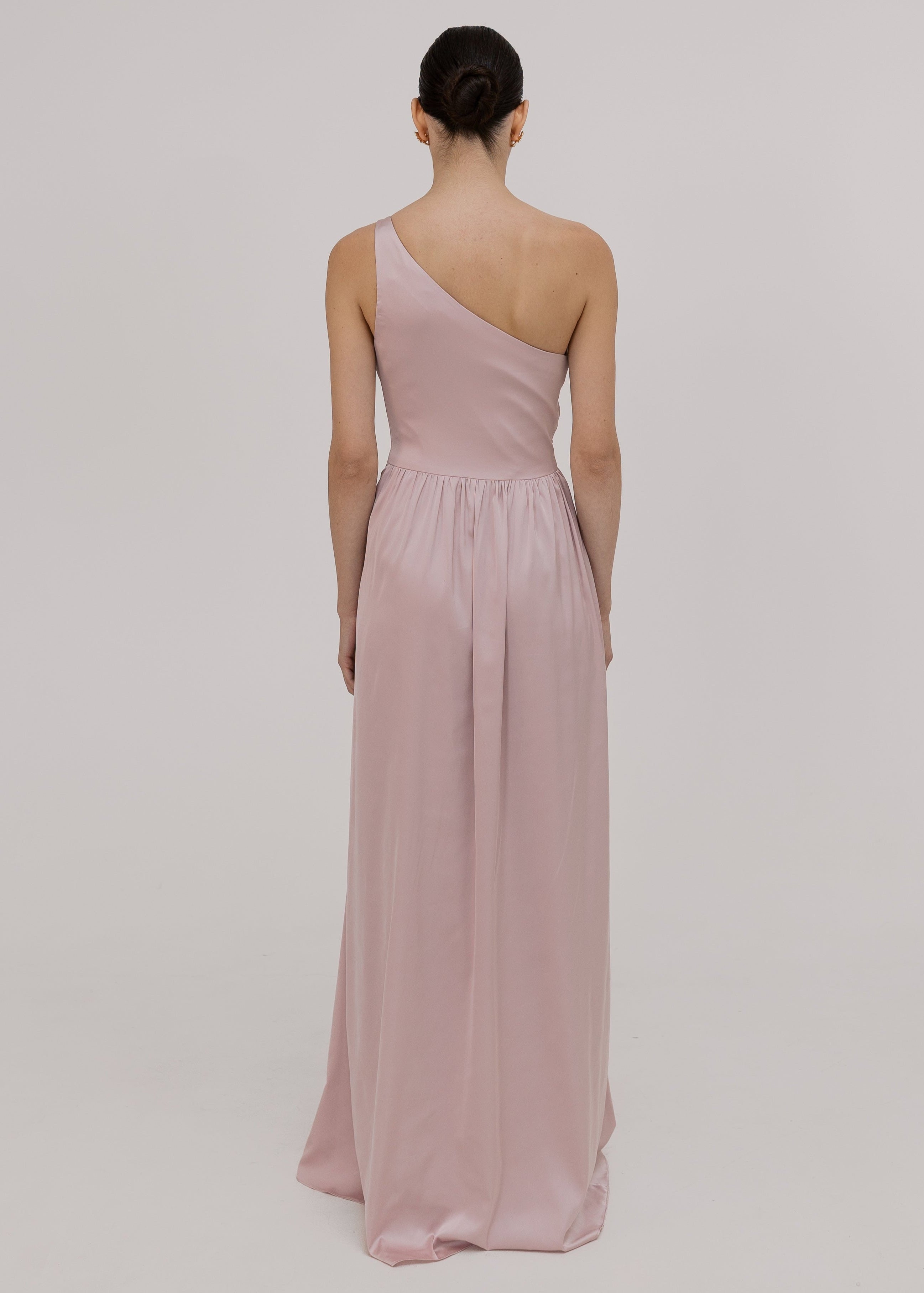 Woman wearing a pink one-shoulder satin bridesmaid dress by TH&TH.