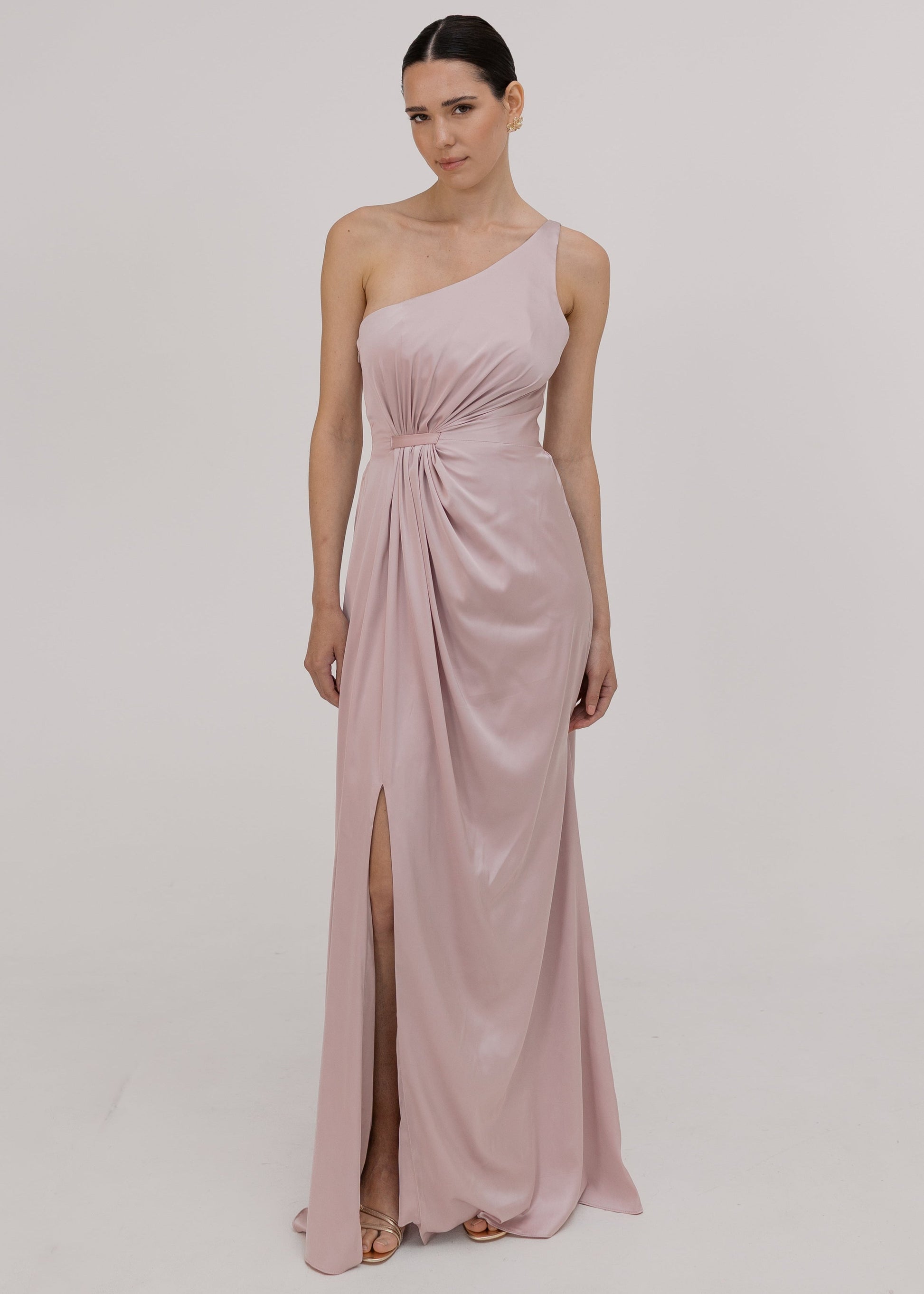 Woman wearing a one-shoulder pink bridesmaid dress with a slit by TH&TH.