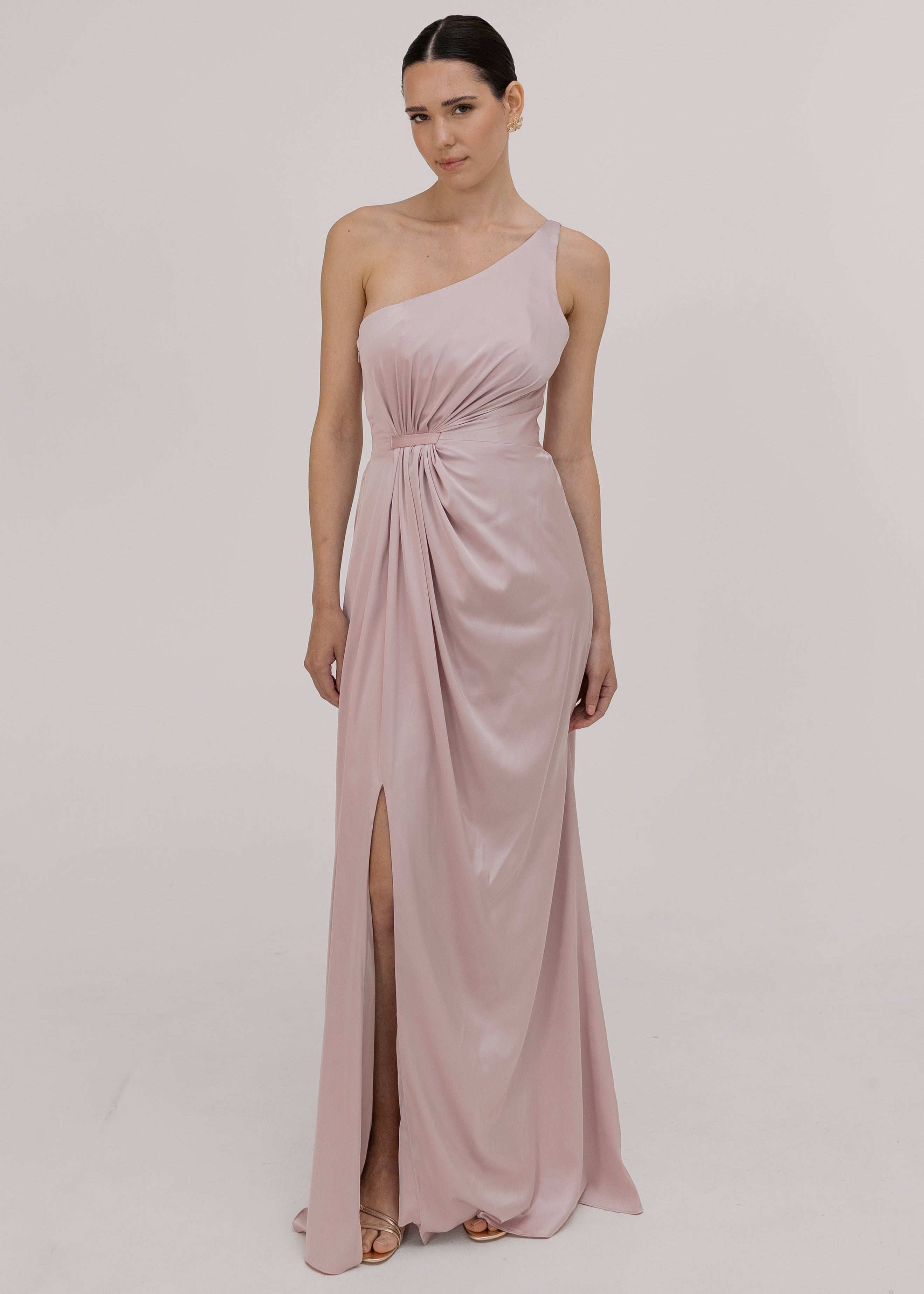 Woman wearing a one-shoulder pink bridesmaid dress with a slit by TH&TH.