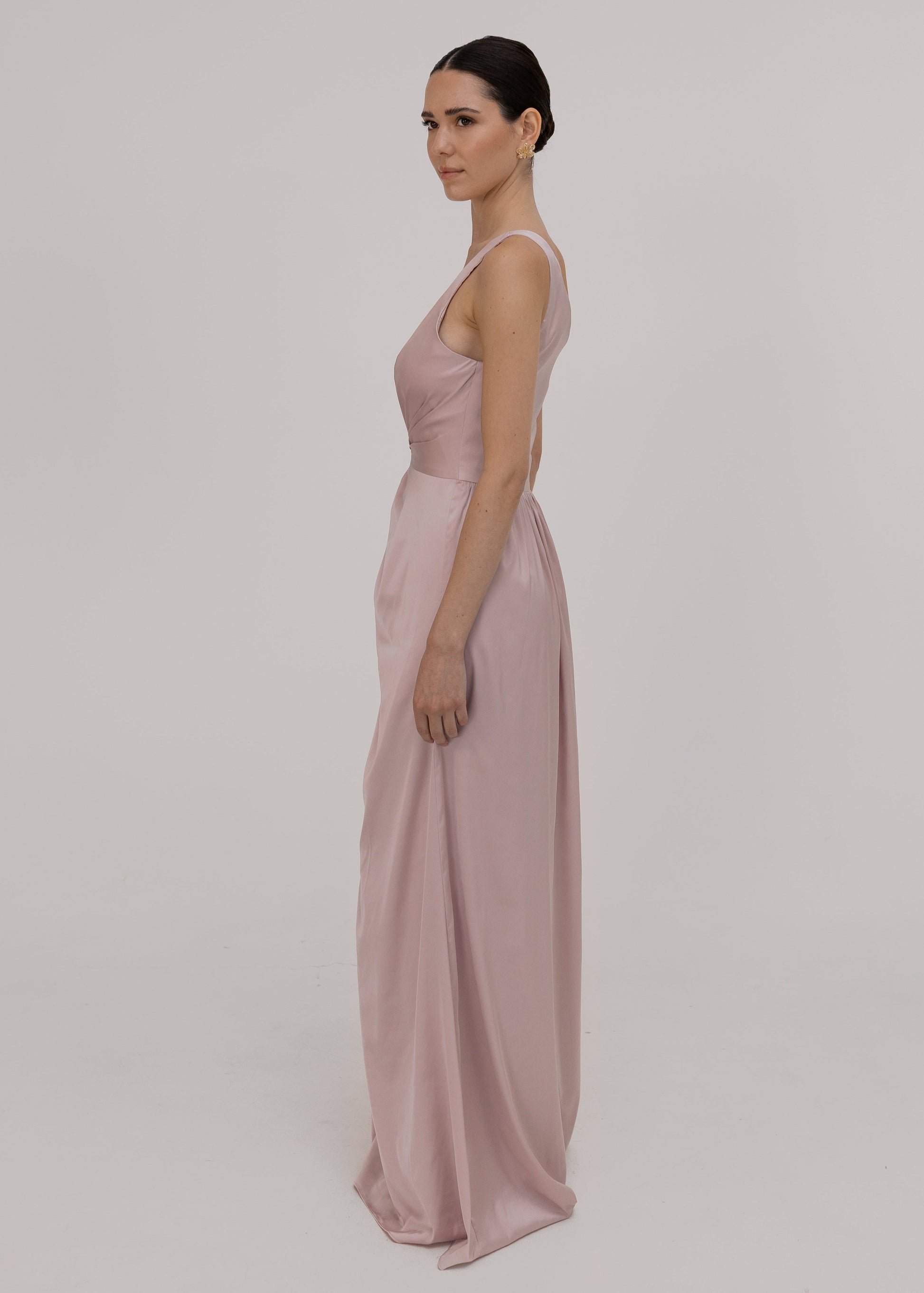 Woman wearing a long, light pink satin bridesmaid dress by TH&TH.