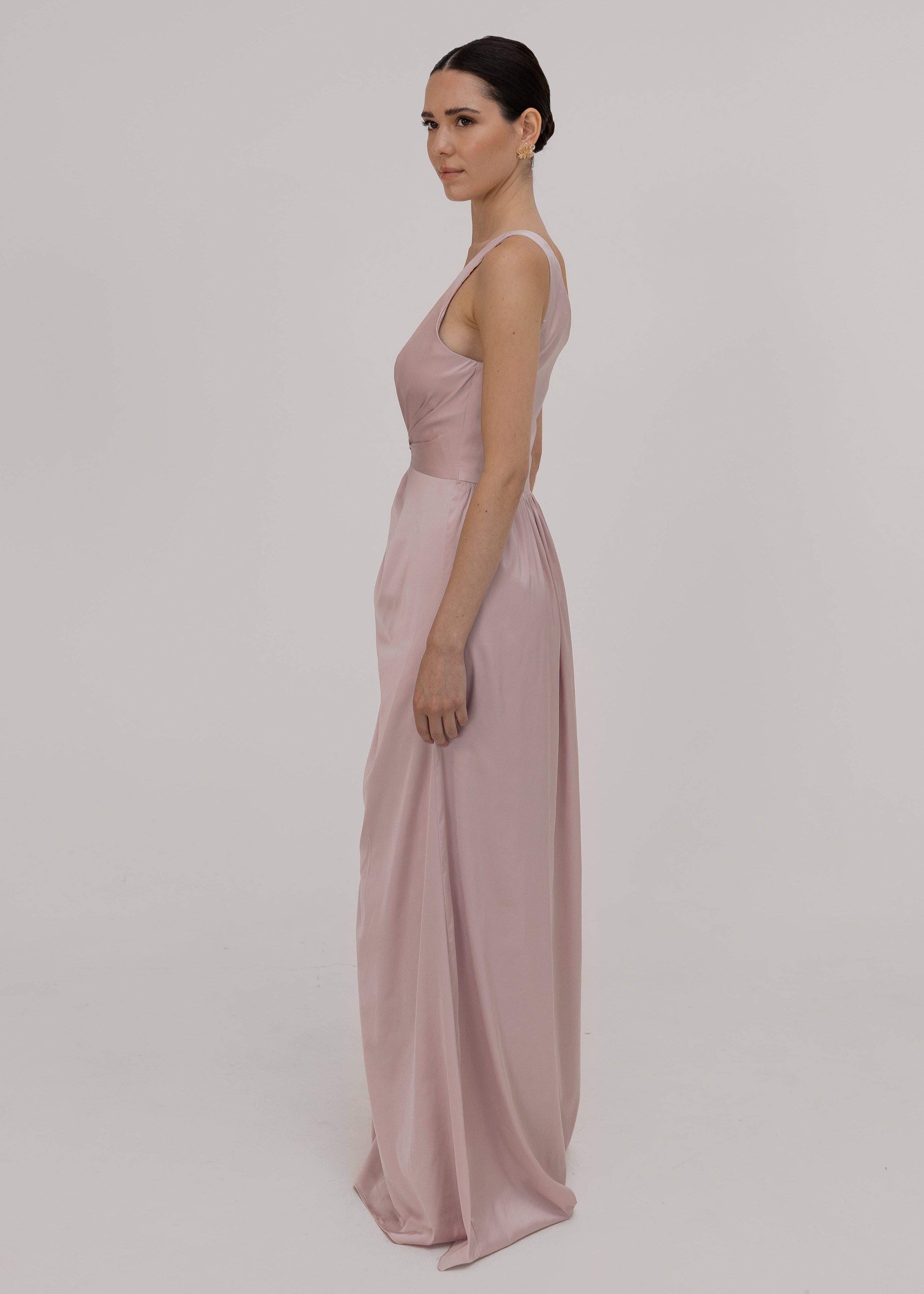 Woman wearing a long, light pink satin bridesmaid dress by TH&TH.