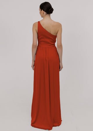 Woman wearing a terracotta satin one-shoulder bridesmaid dress on a plain background.