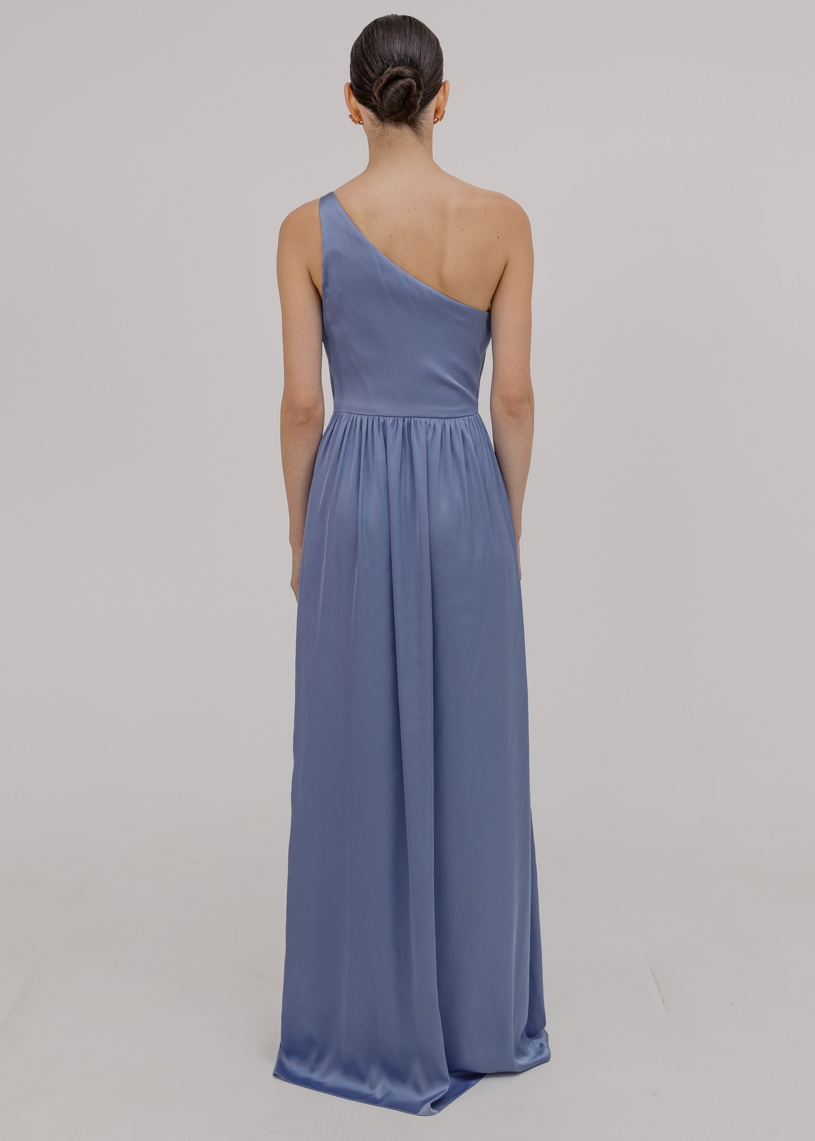 Woman wearing a long blue bridesmaid dress with one shoulder, in french blue satin.