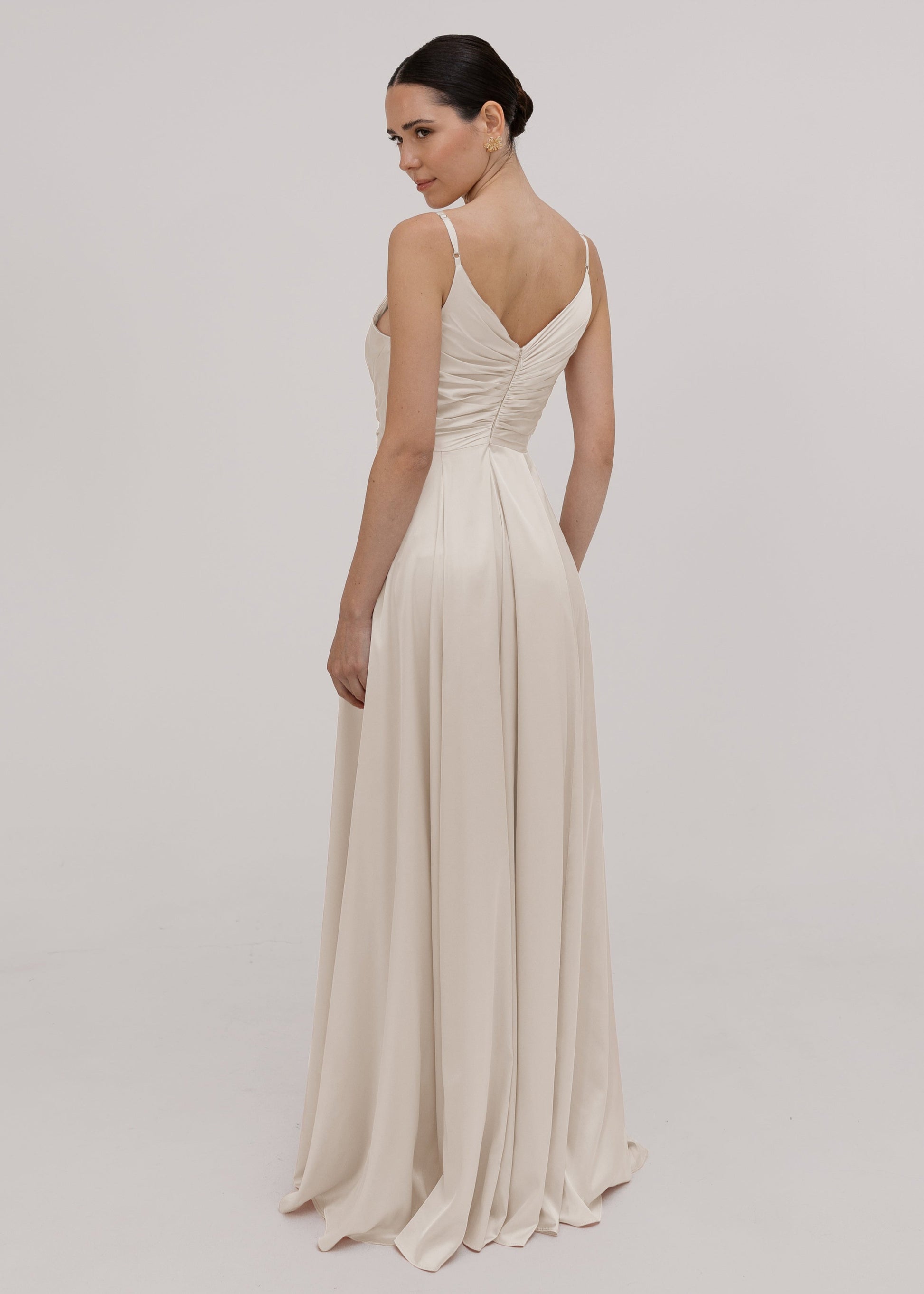Woman wearing a long, flowing oyster satin bridesmaid dress by TH&TH
