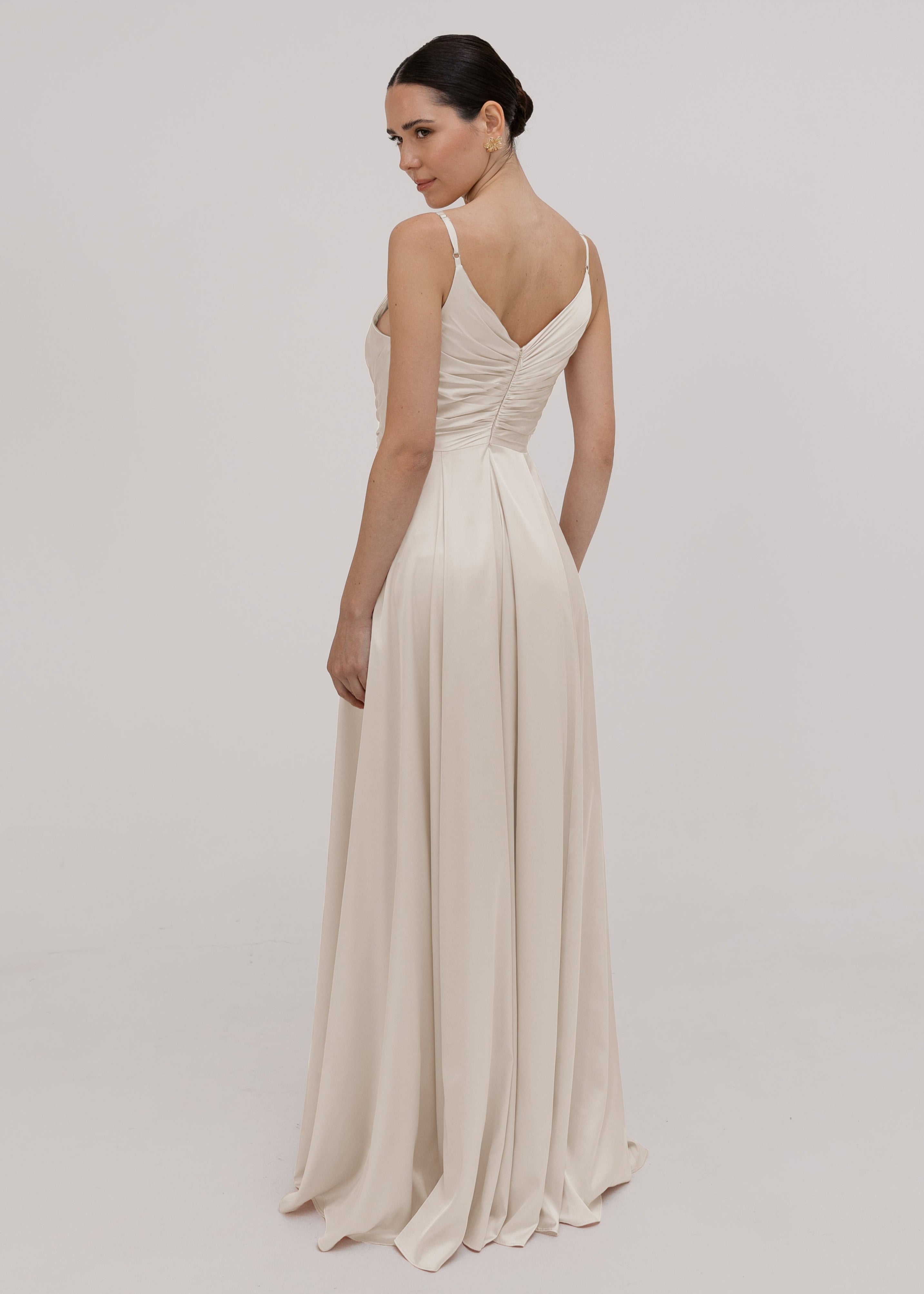 Woman wearing a long, flowing oyster satin bridesmaid dress by TH&TH
