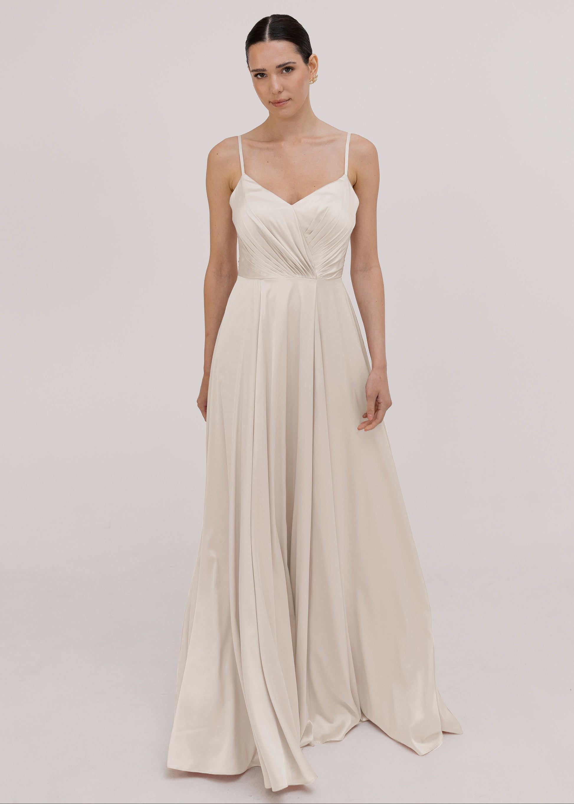 Woman wearing a long, light-colored oyster satin bridesmaid dress by TH&TH.
