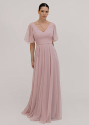 Woman wearing a long smoked blush pink bridesmaid dress with V neck and full skirt in chiffon.