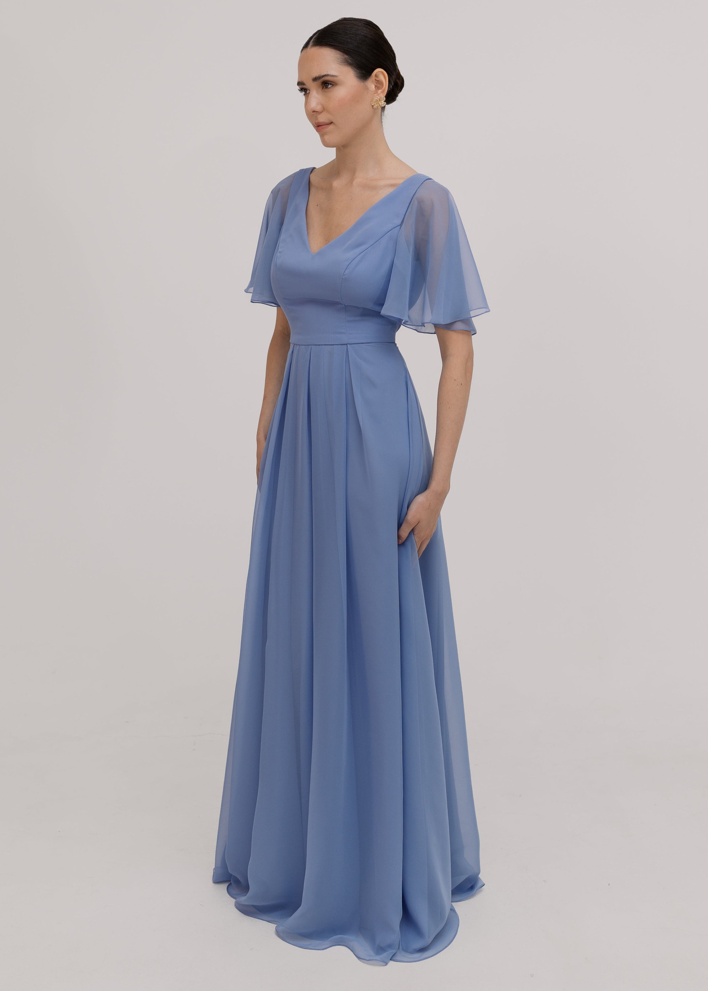 Woman wearing a long blue dress with short sleeves, V neck and a line skirt in french blue chiffon.