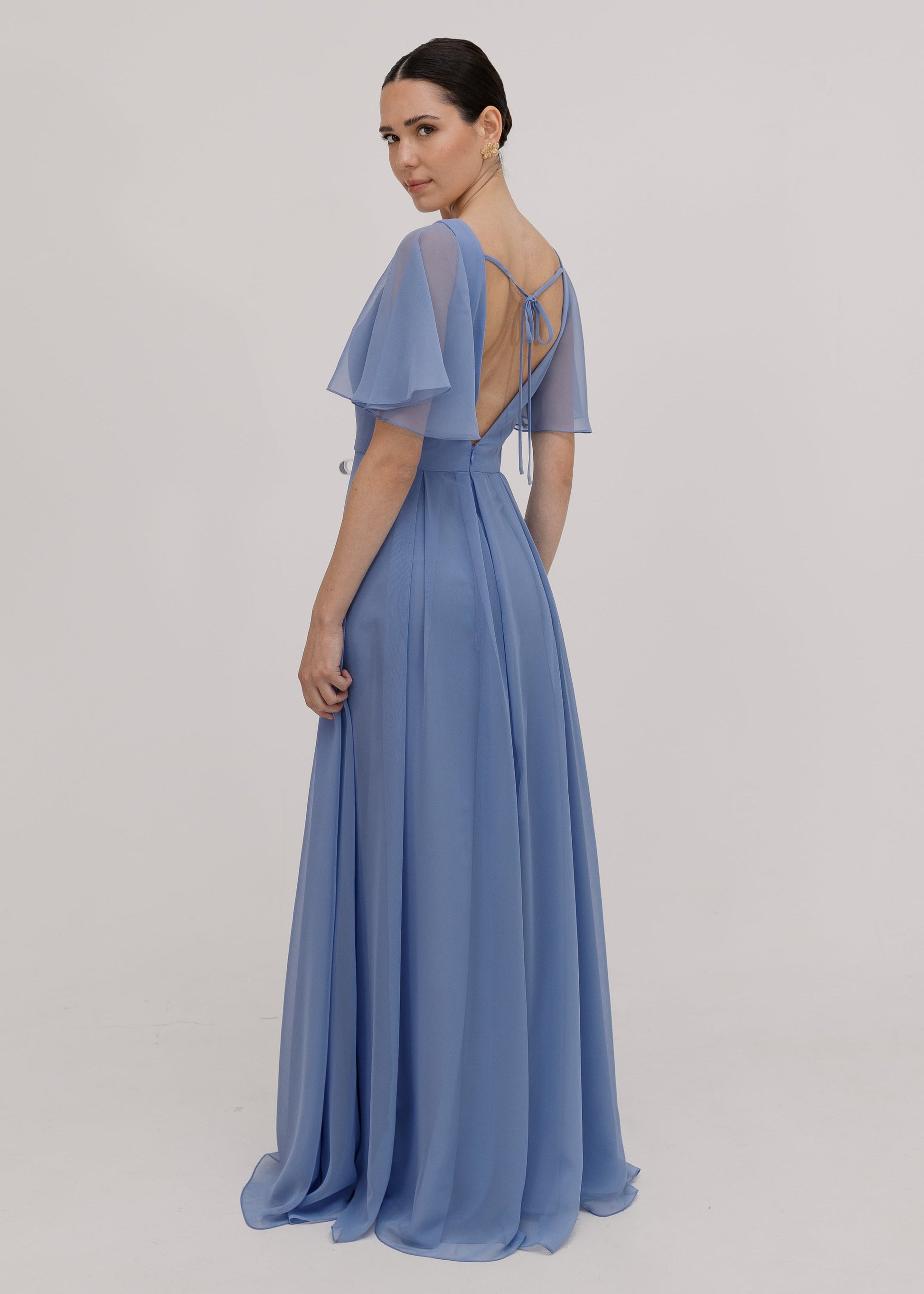 Woman wearing a long blue dress with short sleeves, V neck and a line skirt in french blue chiffon.