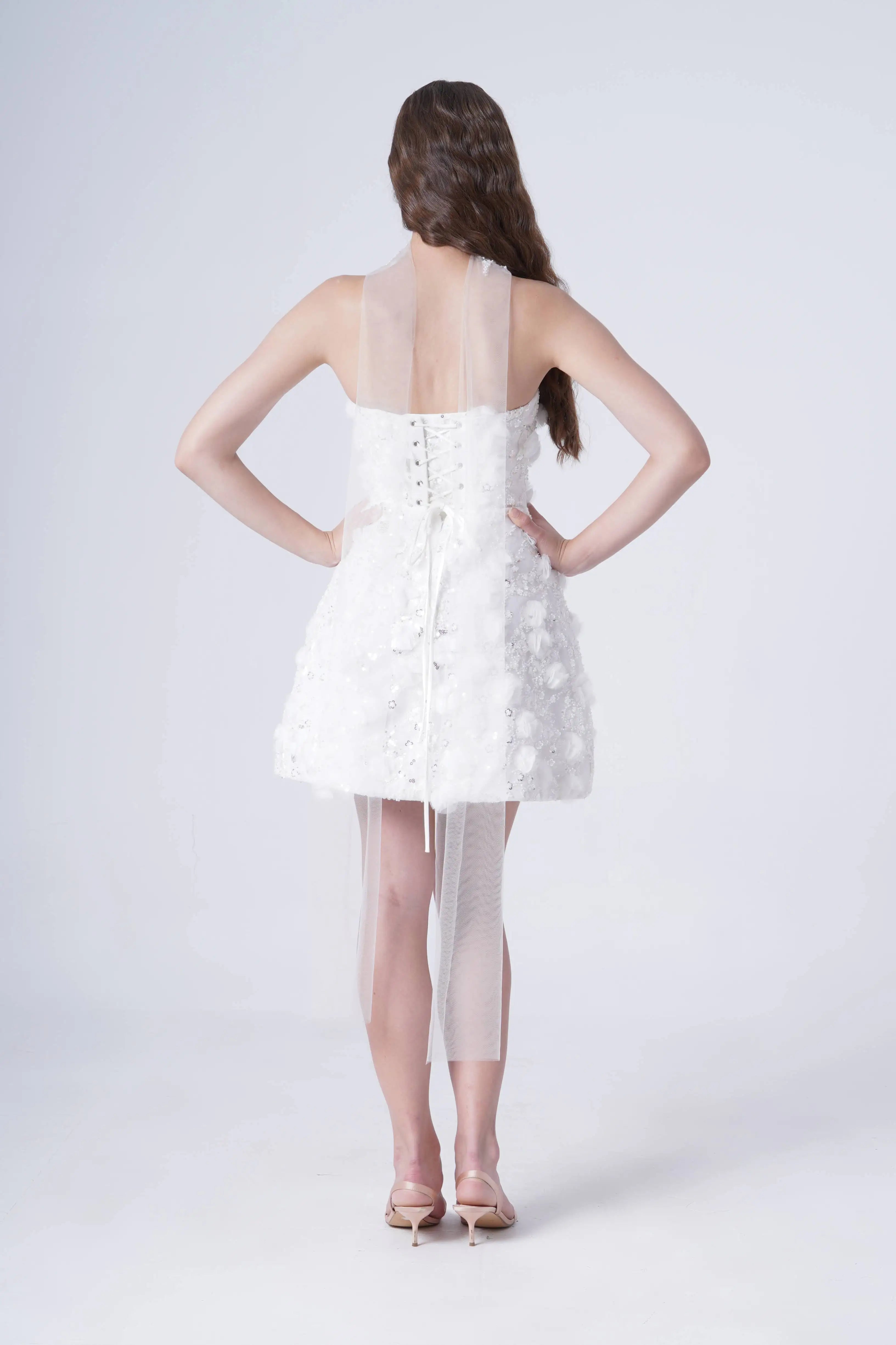 Woman wearing a white dress with sheer panels on a white background
