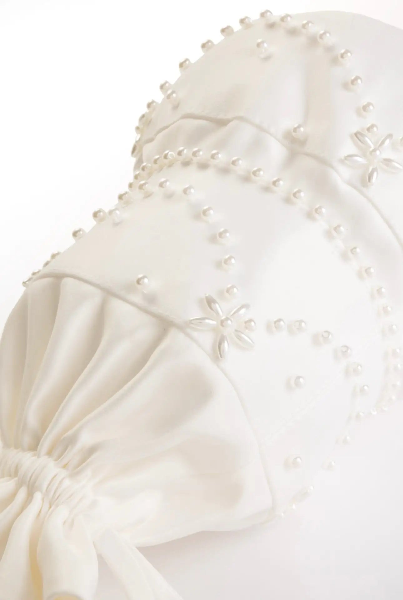 A close-up of the TH&TH 'Wedding Cake' Embellished Bag in Ivory, featuring white pearl details, raised floral patterns, and elegant ruching with a gathered bottom.