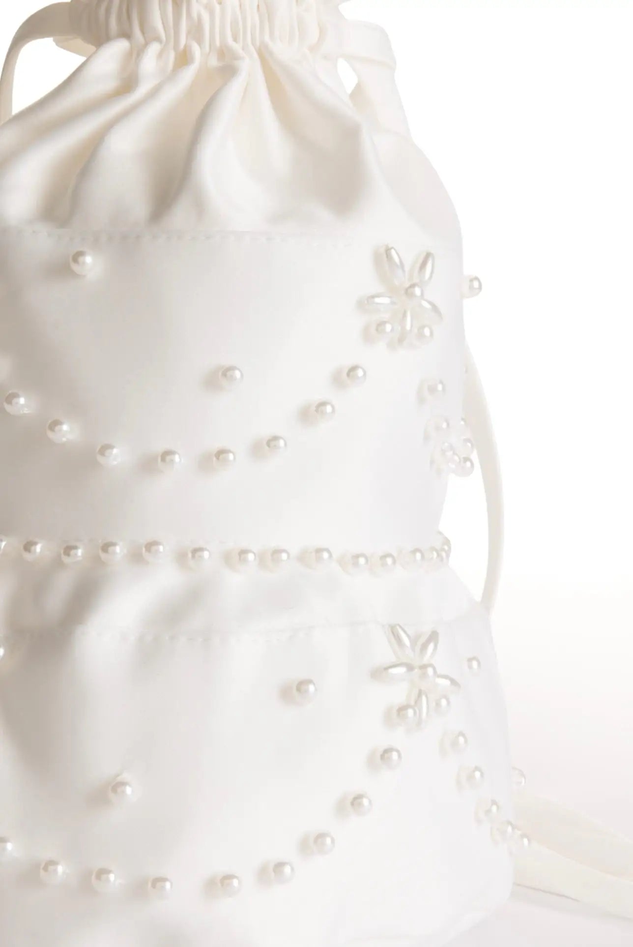 A close-up of the TH&TH 'Wedding Cake' Embellished Bag in Ivory, featuring pearl accents and embroidered florals for a soft, elegant look with subtle texture and shine.
