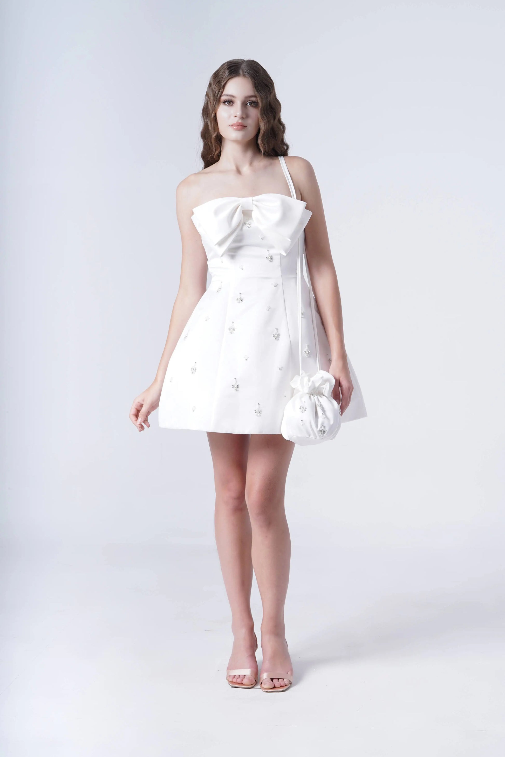 Woman wearing a white strapless dress with a bow detail on a white background