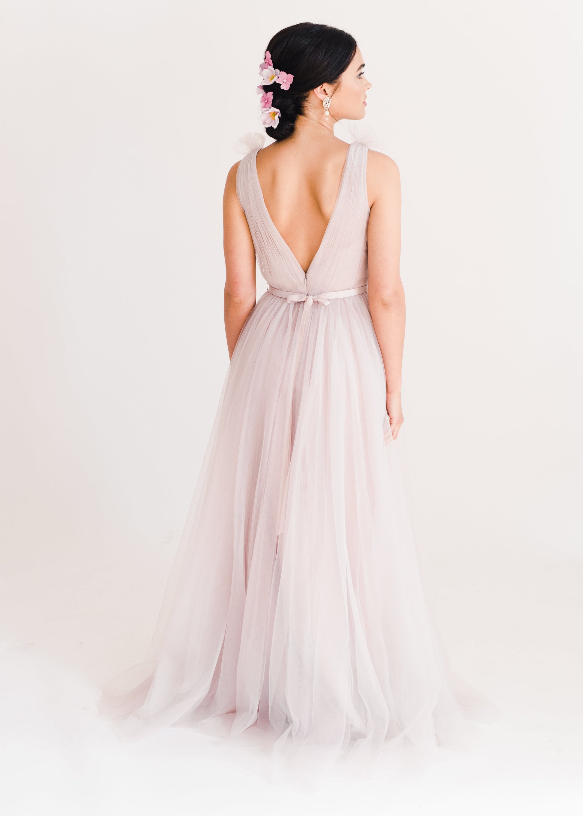Woman wearing a long smoked blush pink bridesmaid dress with V neck and full skirt in tulle.