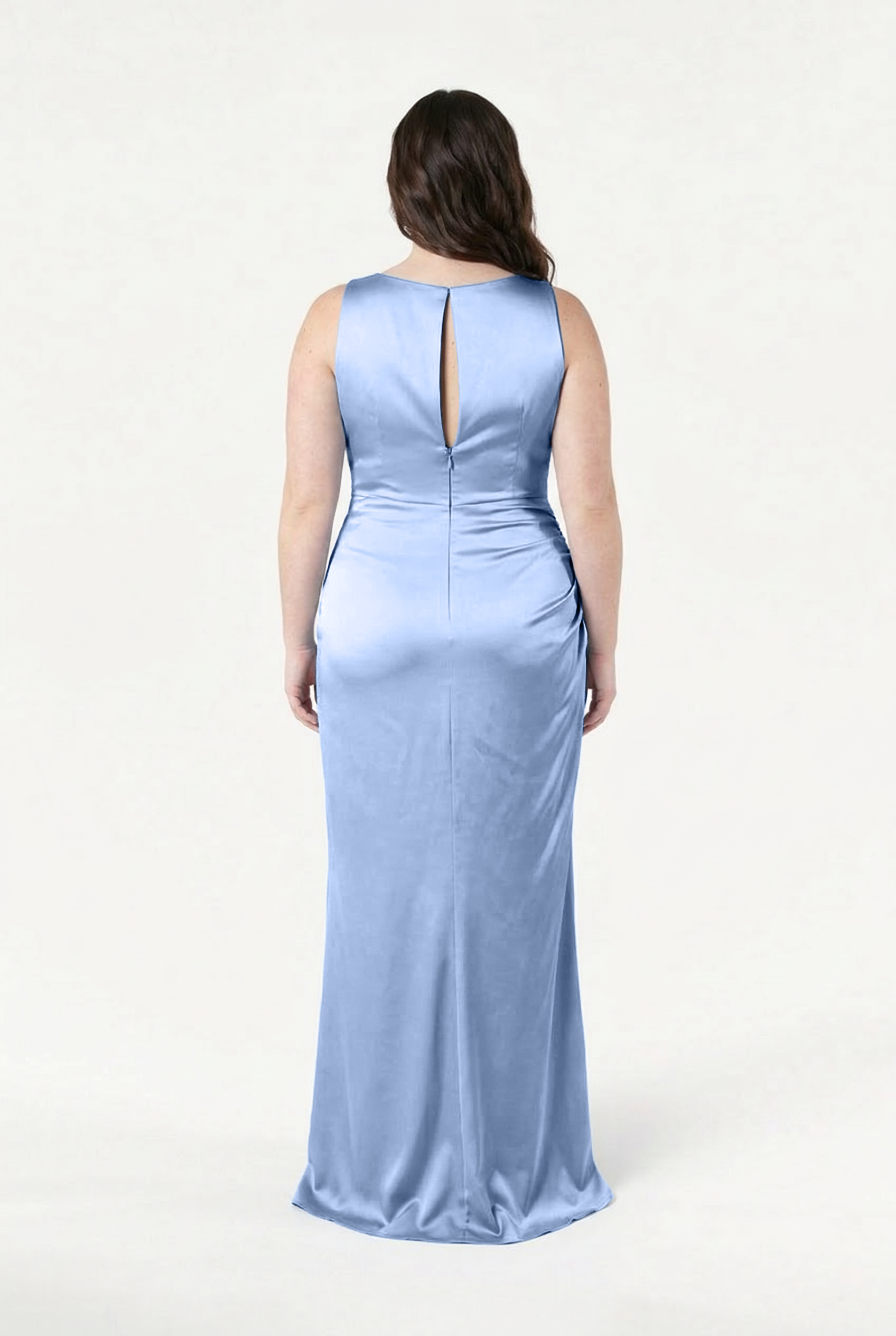 A woman faces away, wearing the TH&TH Nala Bridesmaid Dress in Dusty Blue Satin. This size-inclusive, floor-length gown features a keyhole back and subtle side ruching, set against a plain white background.