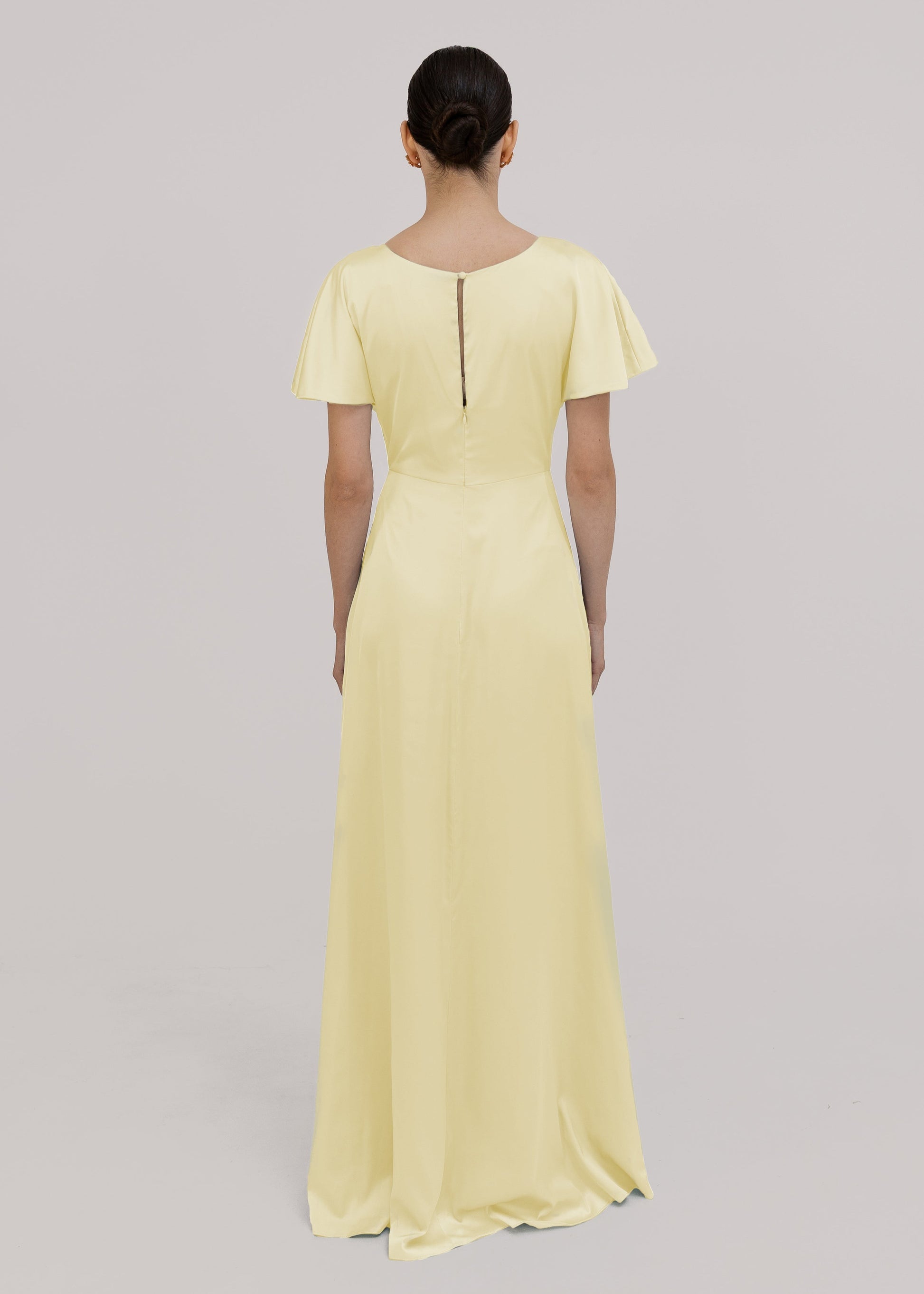 Woman wearing a light yellow dress with short sleeves on a gray background