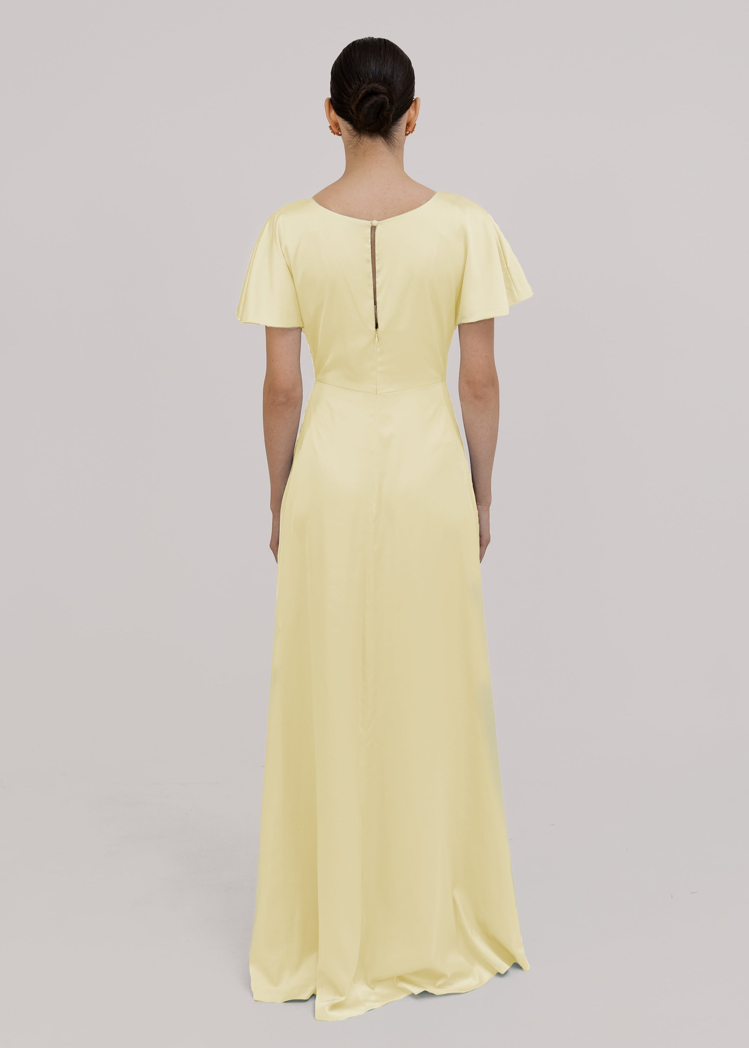 Woman wearing a light yellow dress with short sleeves on a gray background