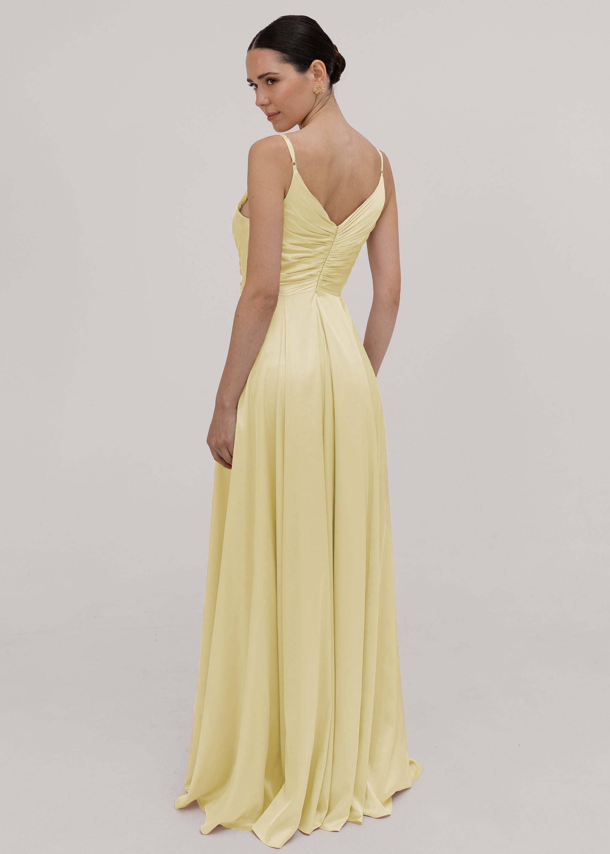 Woman wearing a light yellow evening gown against a plain background